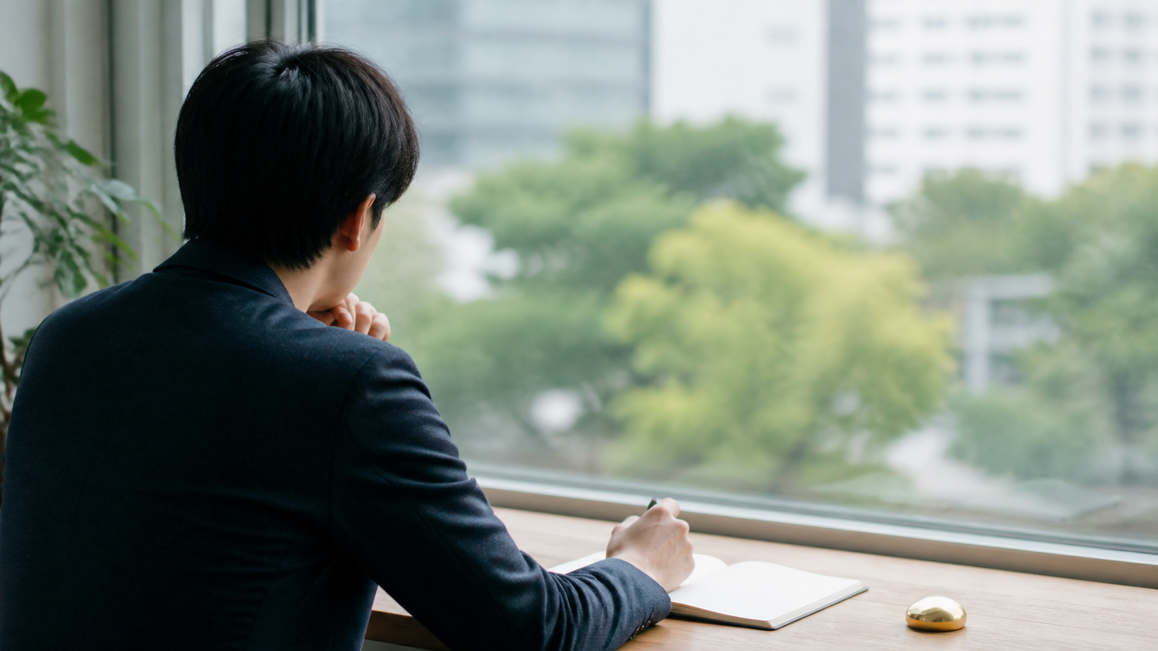 窓辺でノートを読み金融情報を整理する人