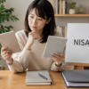 二つの無地のノートを見比べてNISA口座変更を考える人物